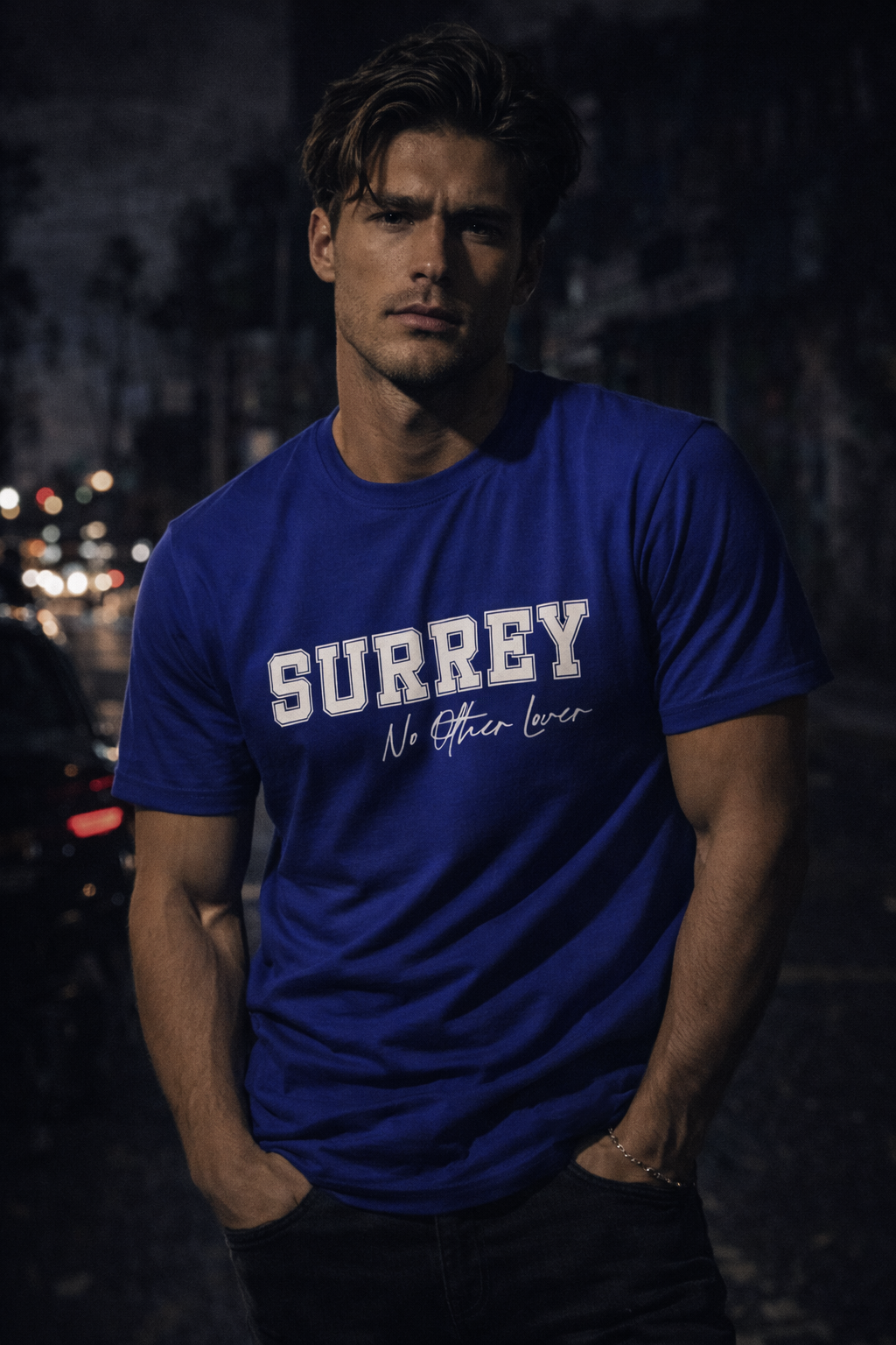 Man wearing a blue No Other Lover Surrey 68' t-shirt against a dark background