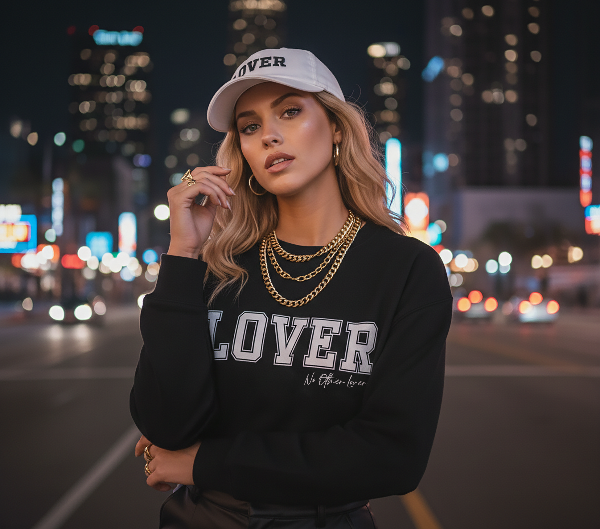 Woman wearing a black 'LOVER' sweatshirt and No Other Lover LOVER White Cotton Baseball Cap with city lights in the background