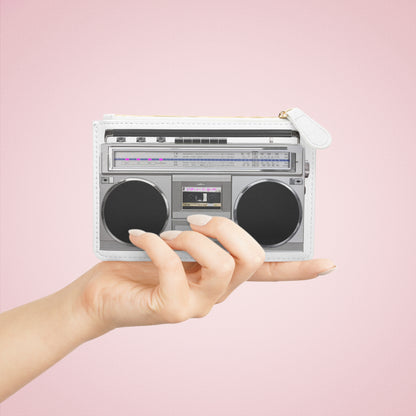 Hand holding a mini boombox-shaped purse against a pink background